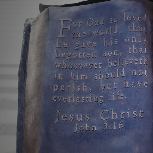 Bible sculpture of metal with a bible verse on it.